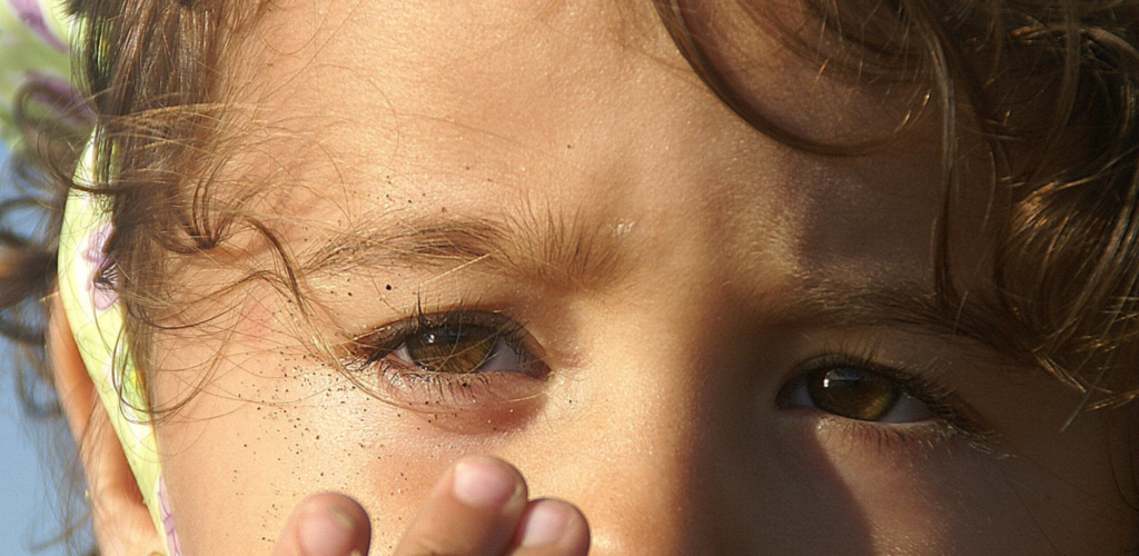 Niña con arena en los ojos simbolizando una urgencia ocular